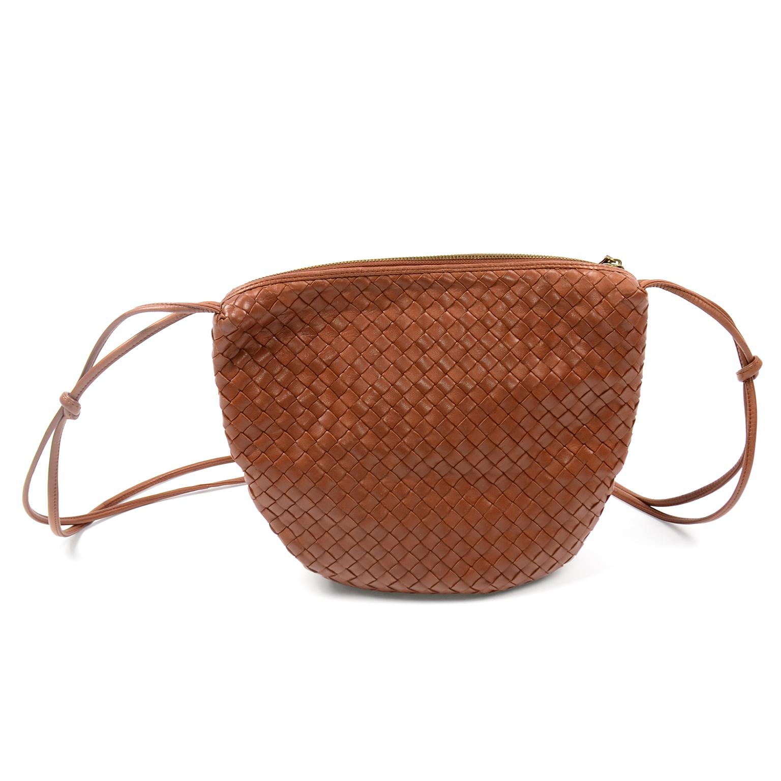 This is a timeless vintage shoulder or crossbody bag by Bottega Veneta, with intrecciato woven leather and a double leather strap that is knotted in three different places. This beautiful  bag has a zip closure on the top with a tassel zipper pull,