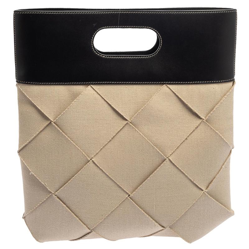 This spectacular tote from Bottega Veneta is perfect for a casual day out with friends. Crafted from beige canvas and black leather with the iconic Intrecciato pattern, the bag carries in-built top handles. It has a spacious interior and an