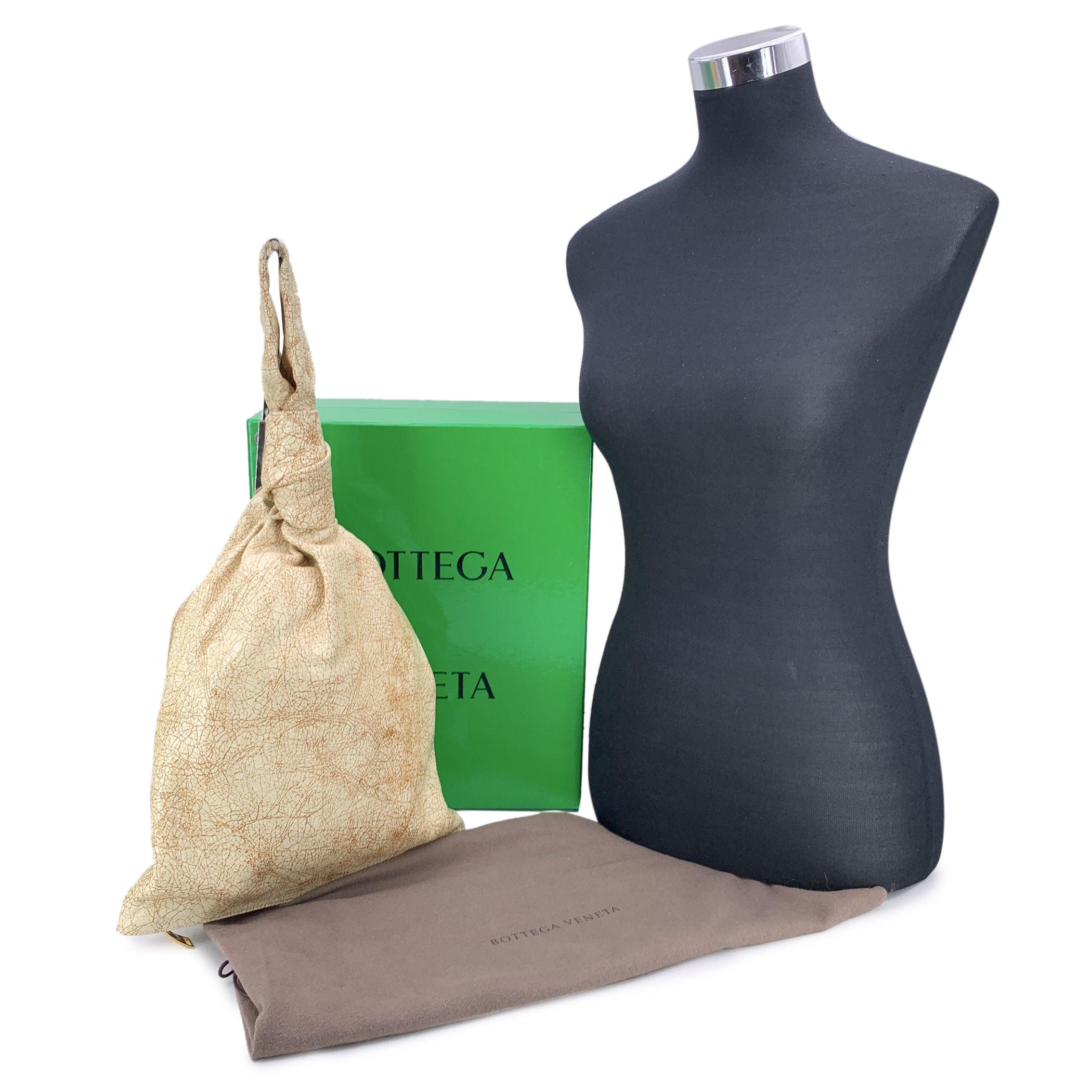 Introducing the Bottega Veneta Leather Twist Knot Handle Clutch Bag in the stunning 'Eggnog' color, an eccentric accessory that effortlessly blends sophistication with a touch of contemporary flair. Crafted from luxurious leather, this bag features