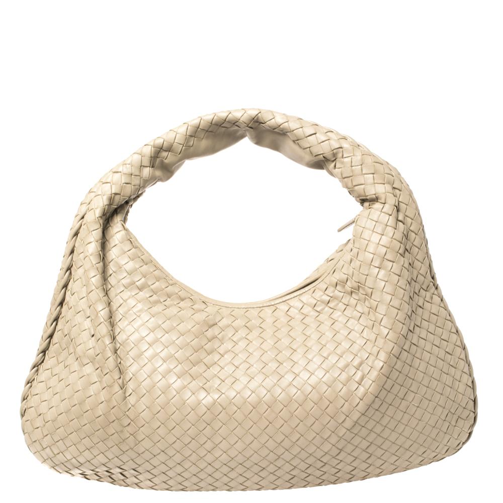 This hobo by Bottega Veneta is durable and practical. Woven from leather in their signature Intrecciato pattern, the beige bag is provided with minimal silver-tone hardware. It features a loop handle and a top zip closure, which secure a spacious