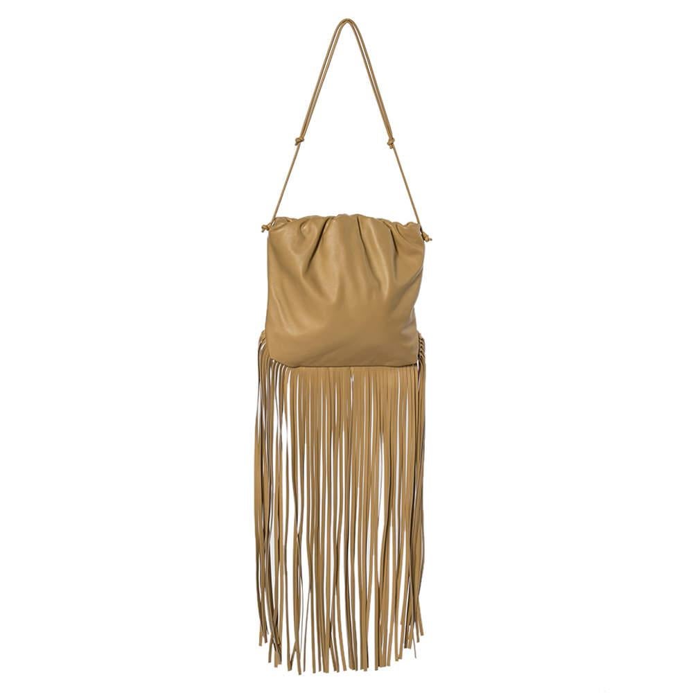 Give yourself a boost of confidence and style with this hobo bag from the house of Bottega Veneta. This bag has been brilliantly designed with beige leather as well as a fringe. It has a single shoulder handle, leather-lined interior and gold-tone