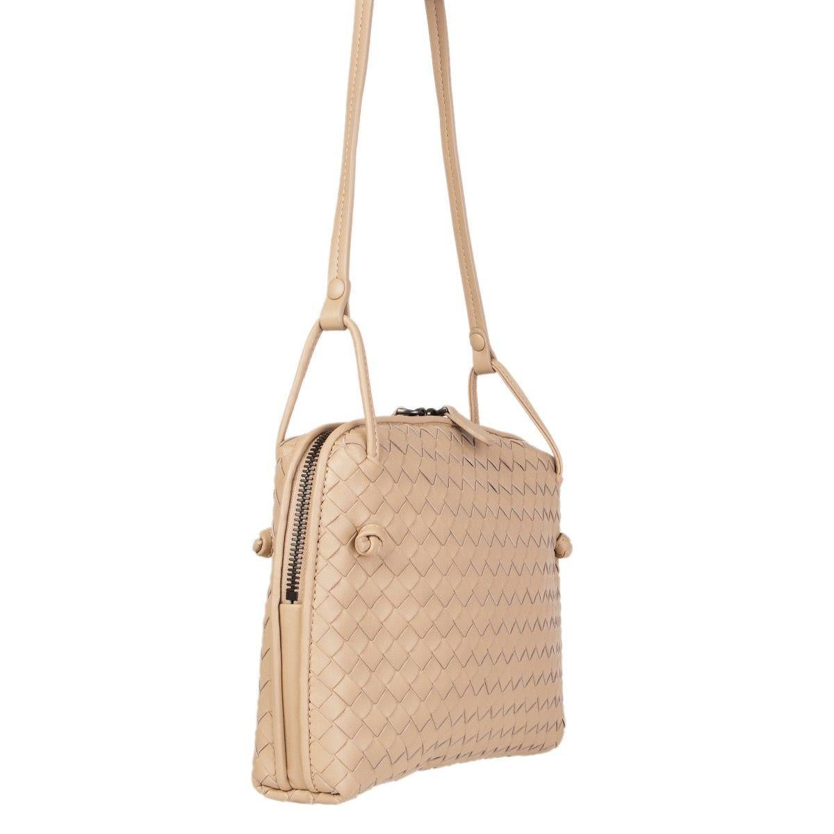 Bottega Veneta 'Nodini' cross-body in sand woven nappa leather. Opens with a two-way zipper on top. Lined in dark taupe suede with one open pocket against the front and a zipper pocket against the back. Has an adjustable shoulder strap. Comes with a