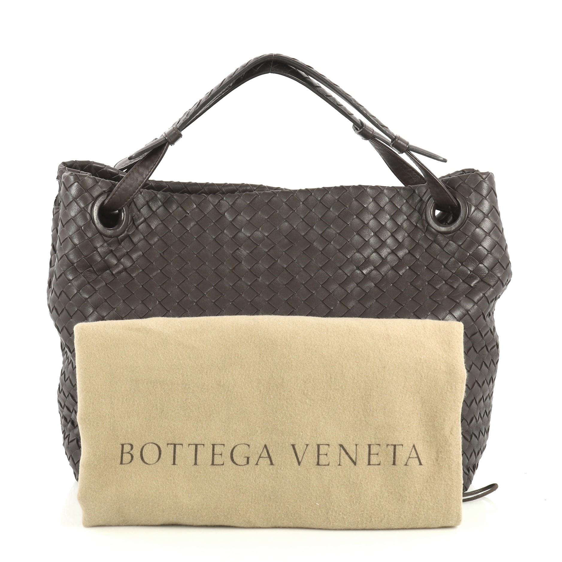 This Bottega Veneta Bella Tote Intrecciato Nappa Large, crafted from brown intrecciato nappa leather, features dual looped handles with braided details and gunmetal-tone hardware. It opens to a neutral suede interior with zip and slip pockets.