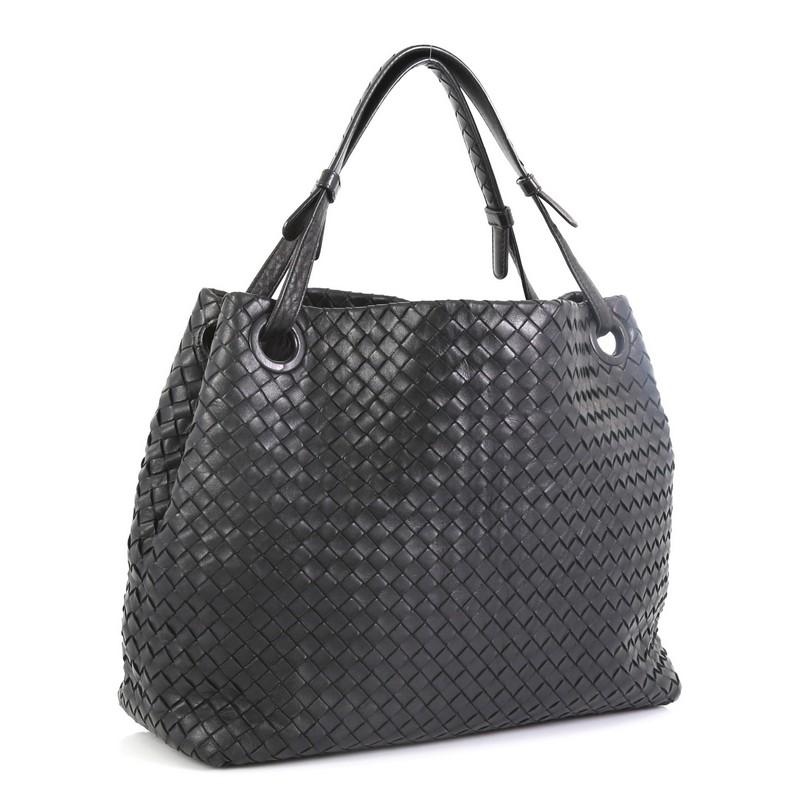 This Bottega Veneta Bella Tote Intrecciato Nappa Medium, crafted from black intrecciato nappa leather, features dual looped handles with braided details and gunmetal-tone hardware. It opens to a neutral suede interior with zip and slip pockets.