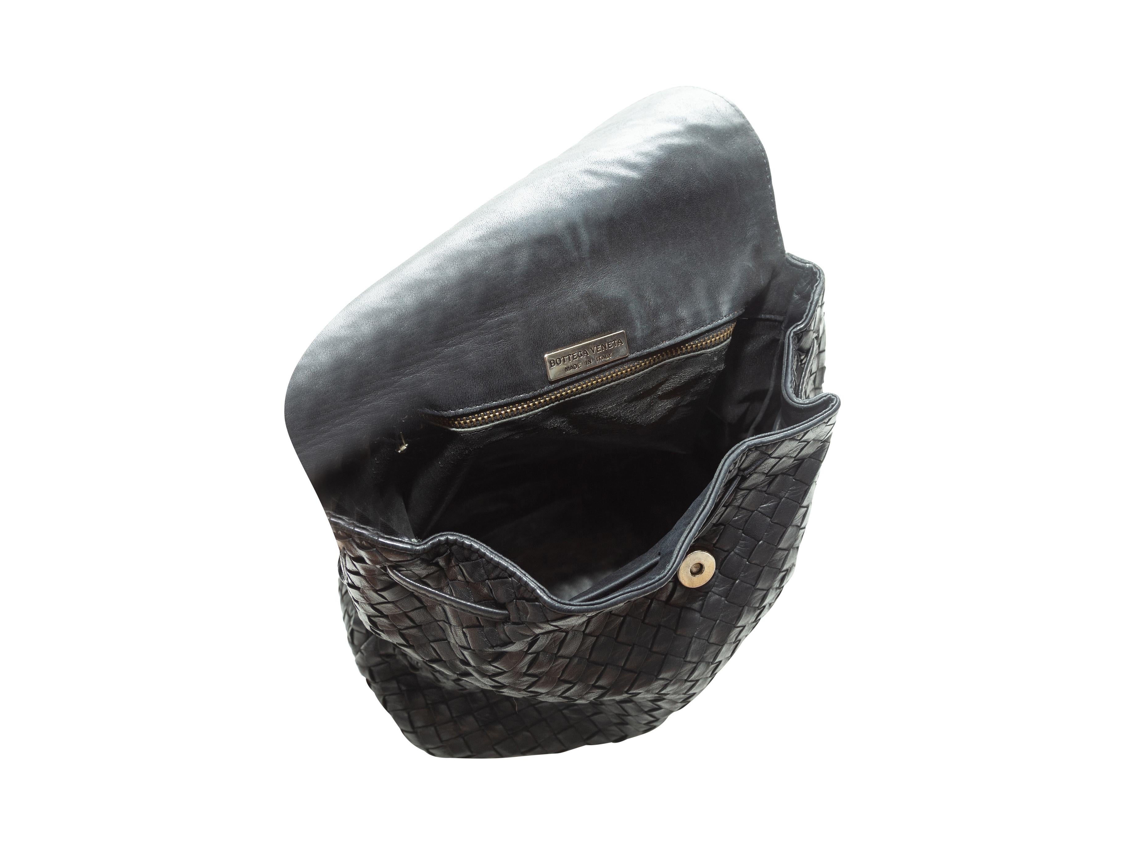 Product Details: Black Intrecciato leather shoulder bag by Bottega Veneta. Interior zip pocket. Knotted shoulder strap. Tassel-accented magnetic closure at front flap. 12