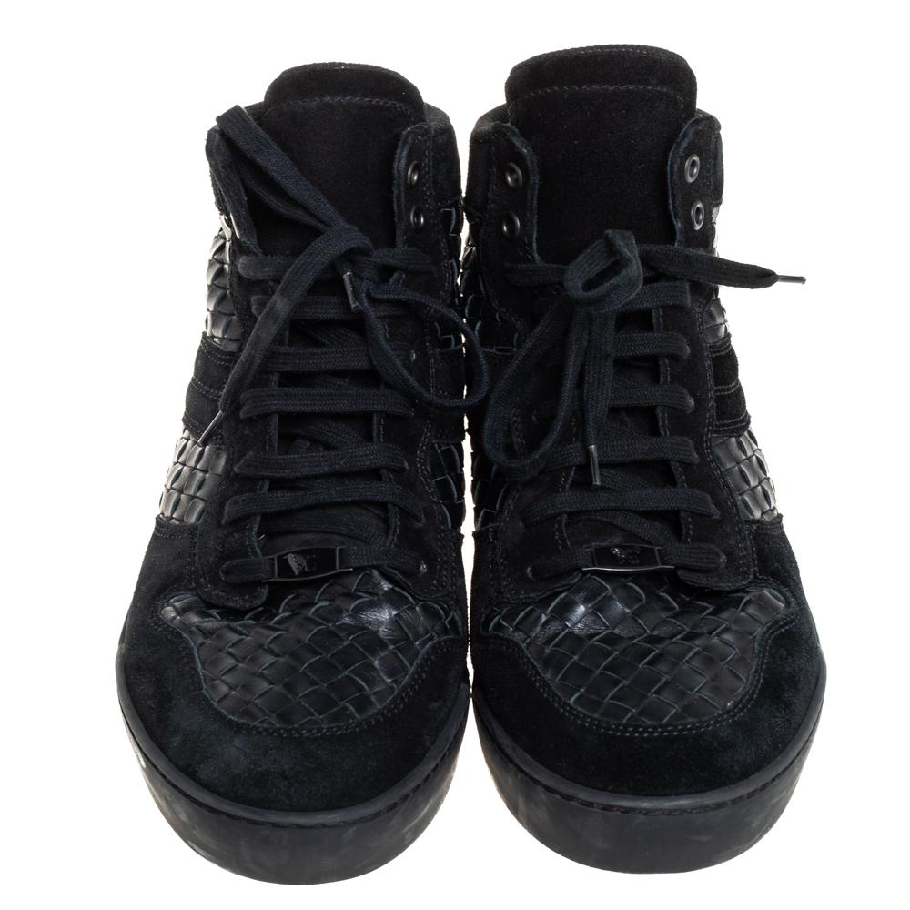 These stunning high-top sneakers by Bottega Veneta have been crafted from suede and leather. They come in a versatile shade of black and feature the brand's iconic Intrecciato weave. They come with a lace-up front, fabric lining, rubber, and leather