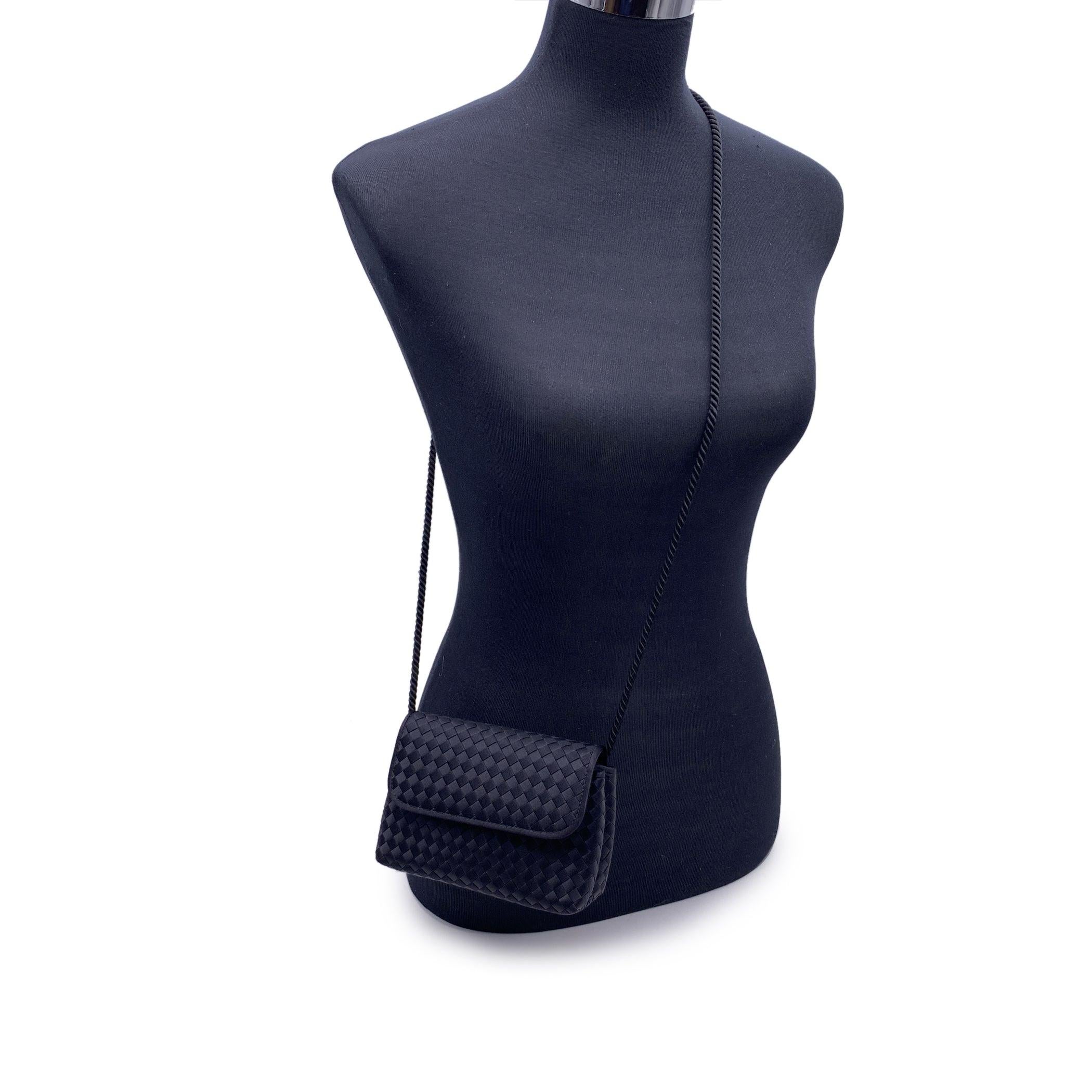 Bottega Veneta 'Intrecciato' shoulder bag in black woven satin. Flap with magnetic button closure. A pocket mirror inside with embossed 'BOTTEGA VENETA' writing. Black satin lining. 2 side open pockets inside. It can be worn as a single cross body