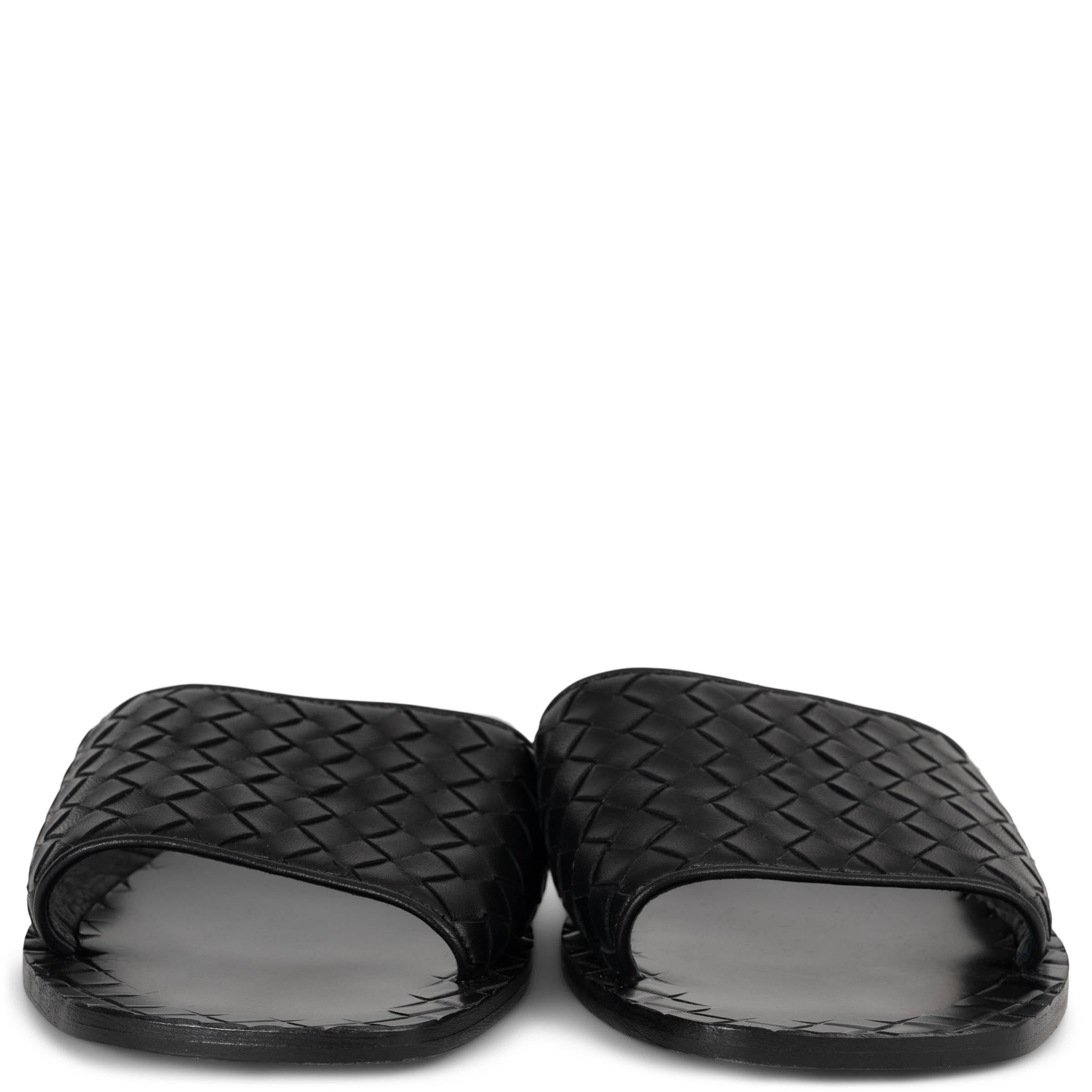 These 100% authentic Bottega Veneta Ravello slide sandals embody understated luxury with a wide black Intrecciato leather strap—a signature of the house’s artisanal craftsmanship. Set on sleek leather soles, they offer a timeless silhouette that