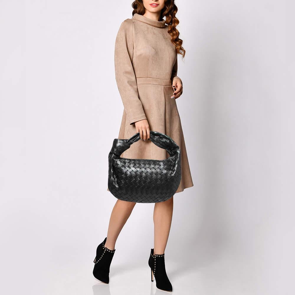 This Bottega Veneta BV Jodie bag is crafted from leather using their signature Intrecciato weaving technique, flaunting a seamless silhouette. This hobo, personifying elegance and subtle charm, is held by a knotted handle. The bag has an interior