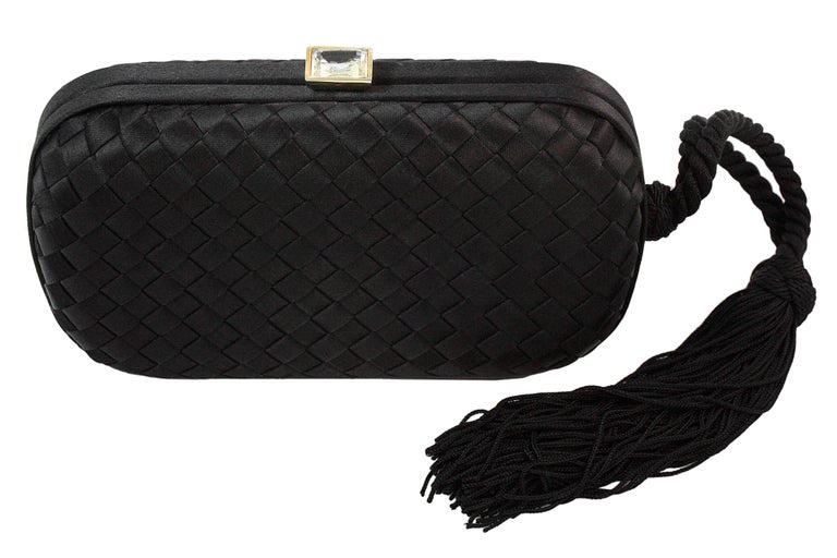 Bottega Veneta 
Woven clutch with tassel 
Black satin 
Rectangular rhinestone covering clip closure 
Made in Italy 
Comes with brown dustbag

