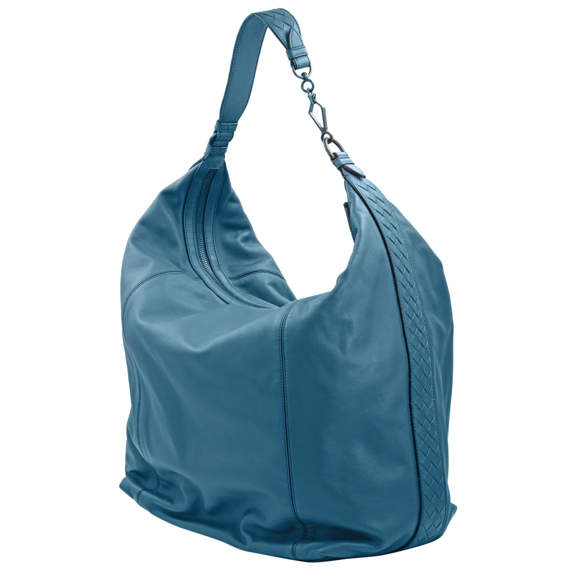 Bottega Veneta blue hobo bag updated with signature Intrecciato detailing on the sides and shoulder strap. Features top zip closure, gunmetal tone hardware, one inside zip pocket, two inside slip pockets and suede lining. Made in Italy.