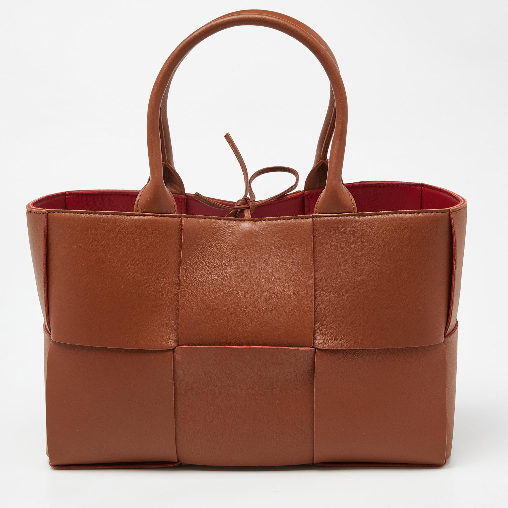 This Arco tote from the House of Bottega Veneta is great for everyday use. It has a brown Intrecciato leather exterior and showcases dual handles, a sturdy shape, and gold-toned hardware. It is provided with a spacious interior.

Includes: Original