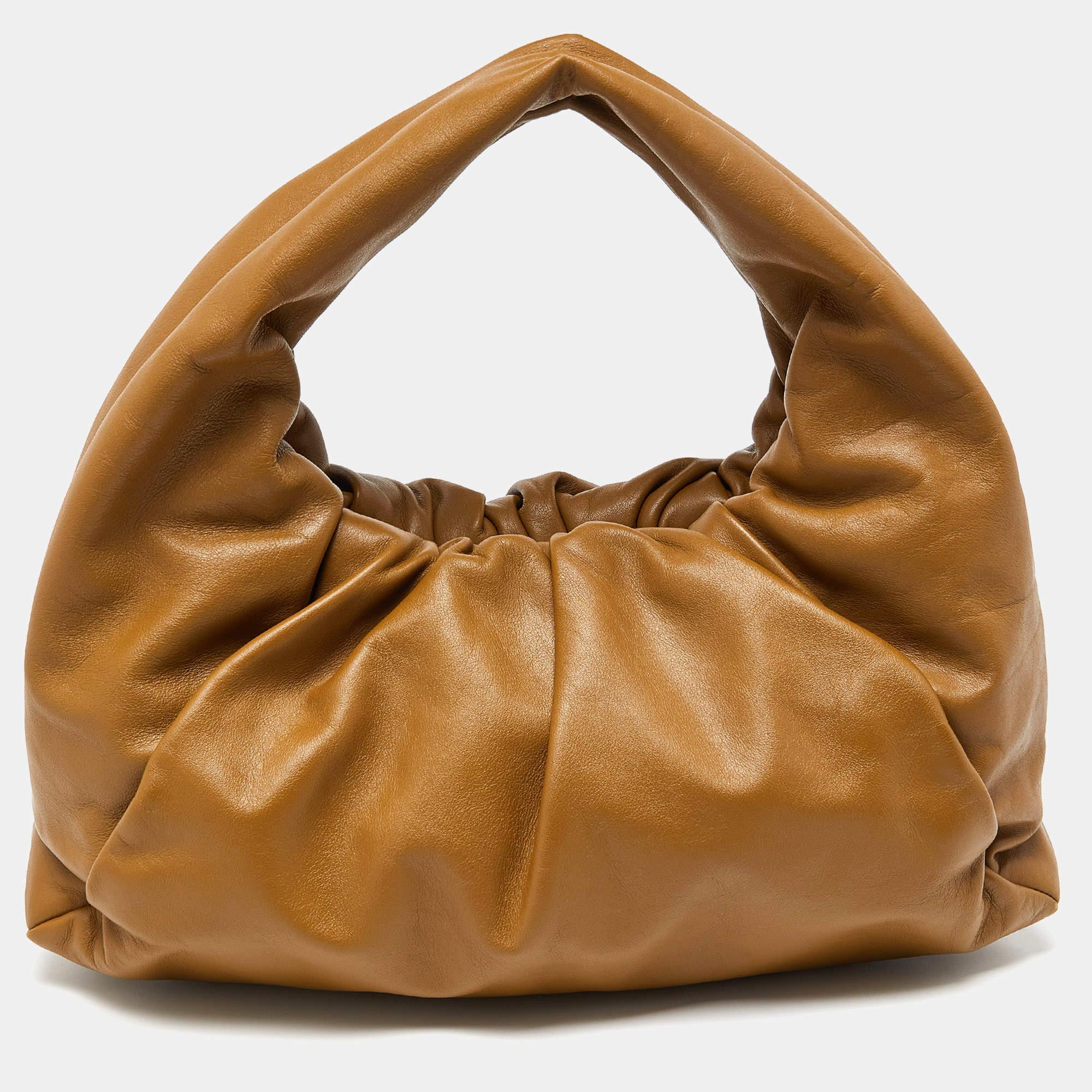 From the House of Bottega Veneta, this shoulder pouch bag offers nothing but impeccable style and practicality to you. Sewn using brown leather into a slouched silhouette, this bag features gold-toned hardware and a single handle. It accommodates a
