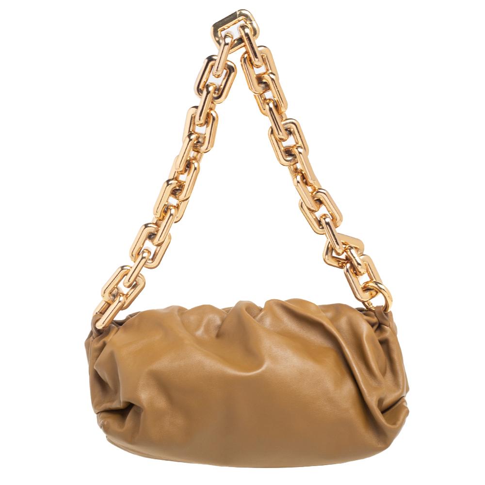The House of Bottega Veneta has created this stunning pouch bag to make an effortless style statement wherever you go. It is made from brown leather and comes with a chunky gold-toned chain strap. Chic and charming, this beautiful pouch bag will amp