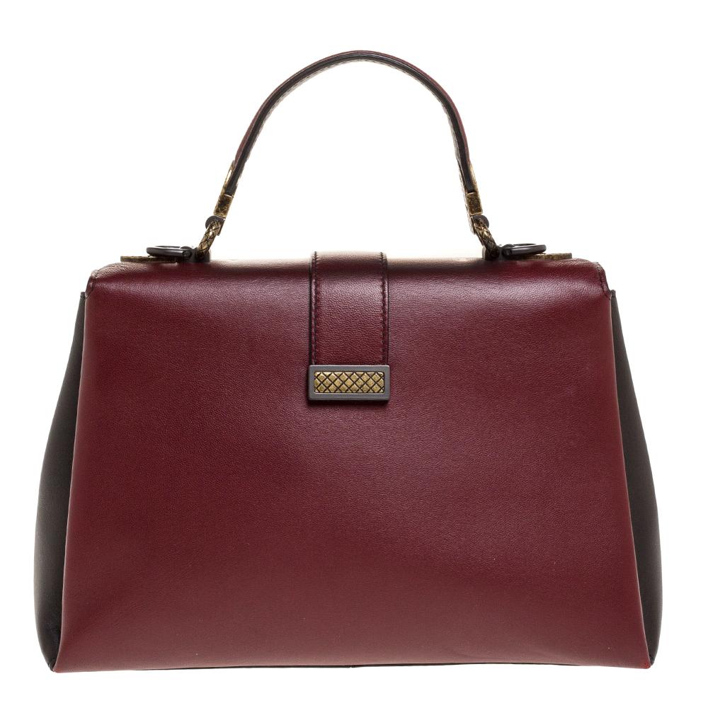 This Bottega Veneta Piazza bag arrives in a structured shape and grand design. Crafted from burgundy & black leather, it has a press-lock on the flap, a top handle and a shoulder strap that is detachable. The flap secures the well-sized suede