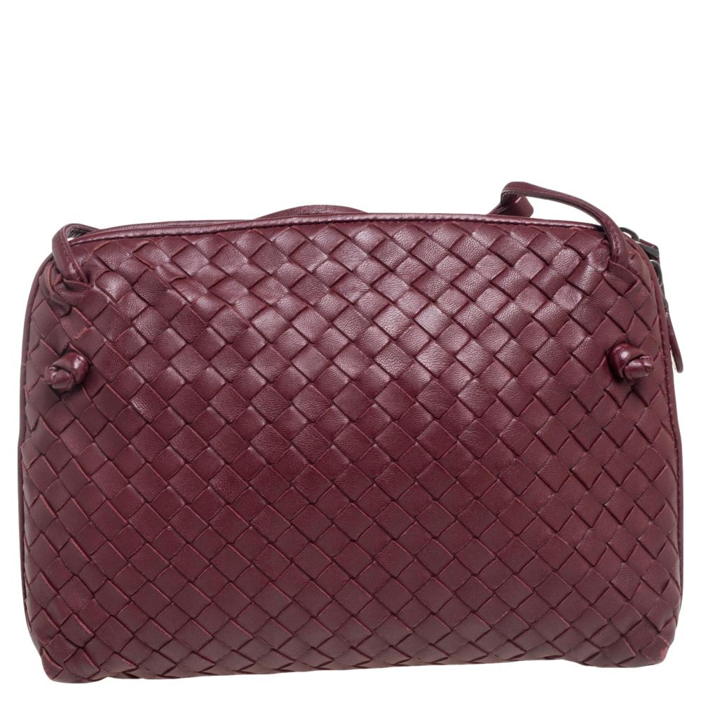 This Nodini bag from Bottega Veneta is crafted from burgundy leather using their signature Intrecciato weaving technique flaunting a seamless silhouette. This shoulder bag, personifying elegance and subtle charm, is held by a long shoulder strap.