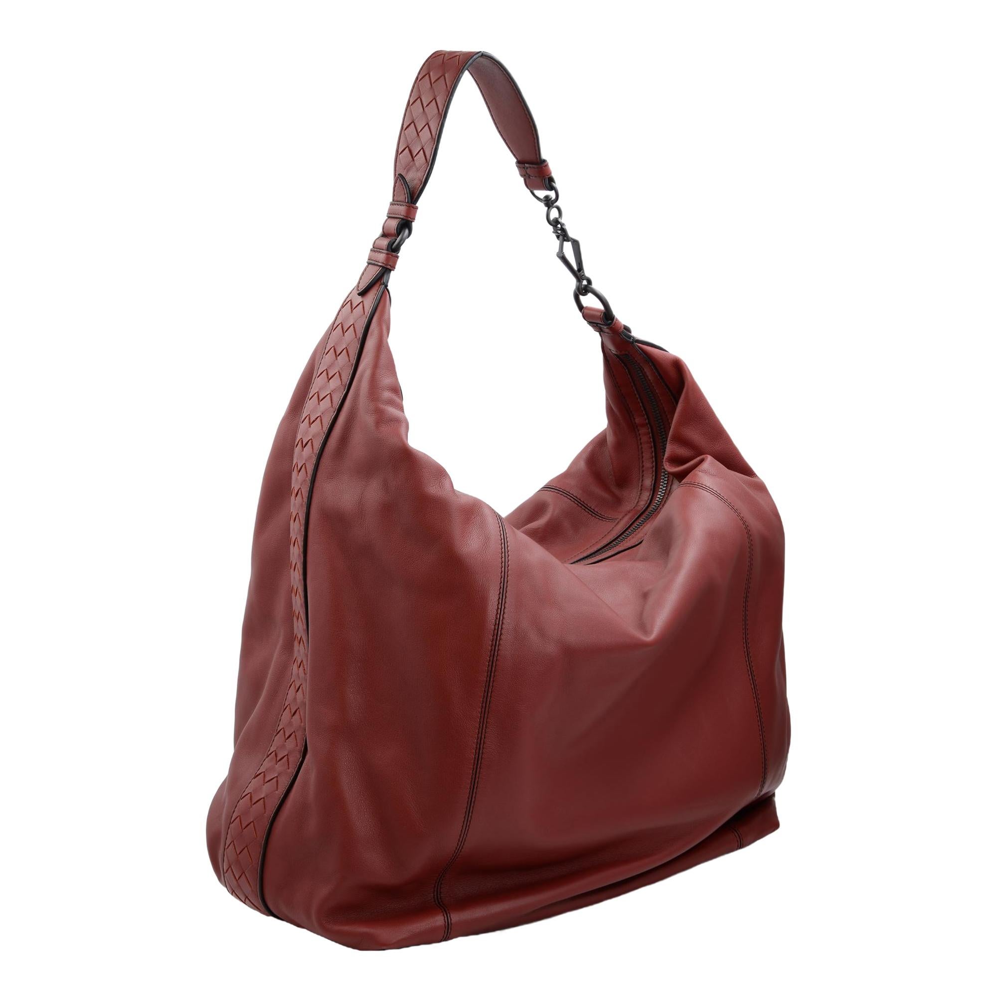 Bottega Veneta burgundy red hobo bag updated with signature Intrecciato detailing on the sides and shoulder strap. Features top zip closure, gunmetal tone hardware, one inside zip pocket, two inside slip pockets and suede lining. Made in Italy.