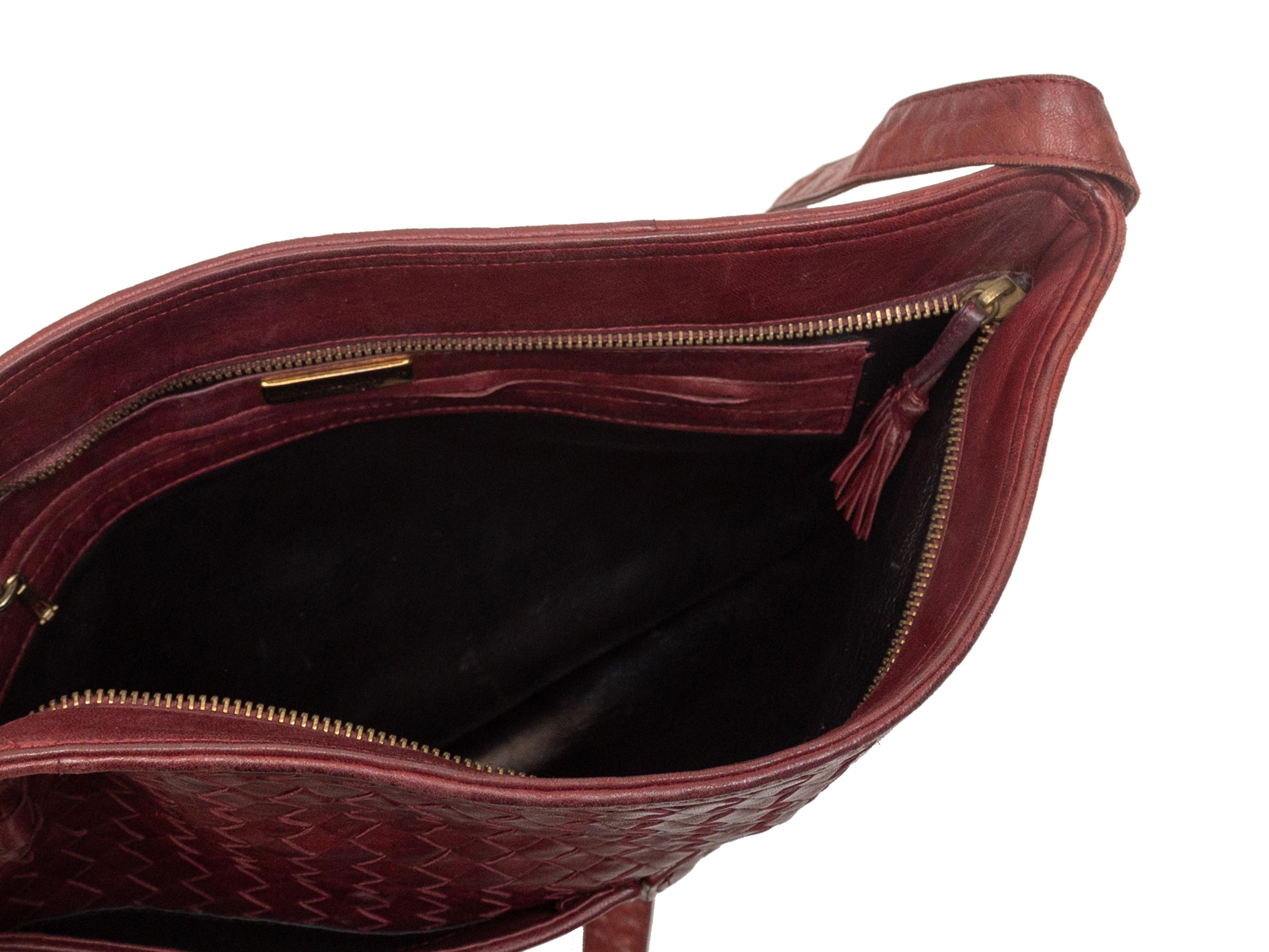 Product details: Vintage burgundy Intrecciato leather shoulder bag by Bottega Veneta. Dual exterior pockets. Zip closure at top. 13