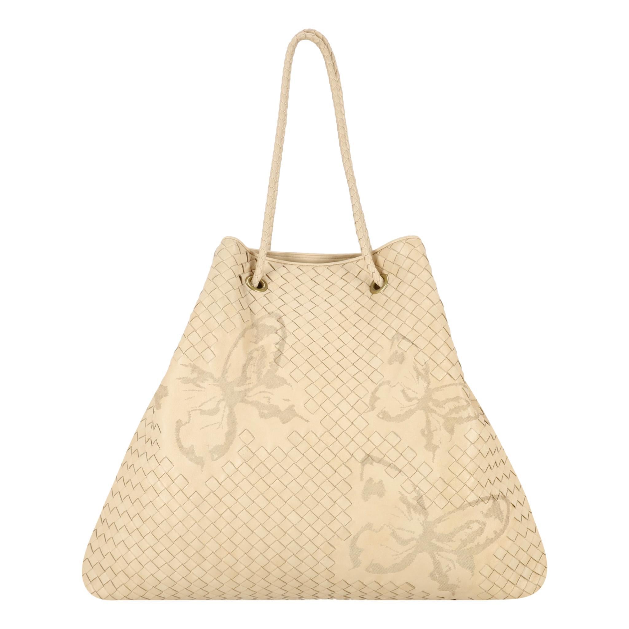 Bottega Veneta Butterfly Embossed Woven Leather Bag

Beige, trapezium shaped tote bag embellished with butterfly embossed motif.

Detailed with aged gold hardware, attached key ring and woven dual handles.

Featuring blue suede interior with slip