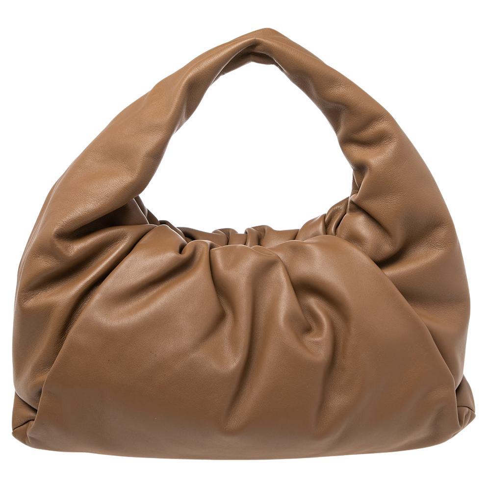 Bottega Veneta's The Shoulder Pouch is a more versatile version of the hit clutch design. Made of camel brown leather, this bag here has a soft, ruched charm and a handle to hold in your hand or shoulder.

Includes: Original Dustbag
