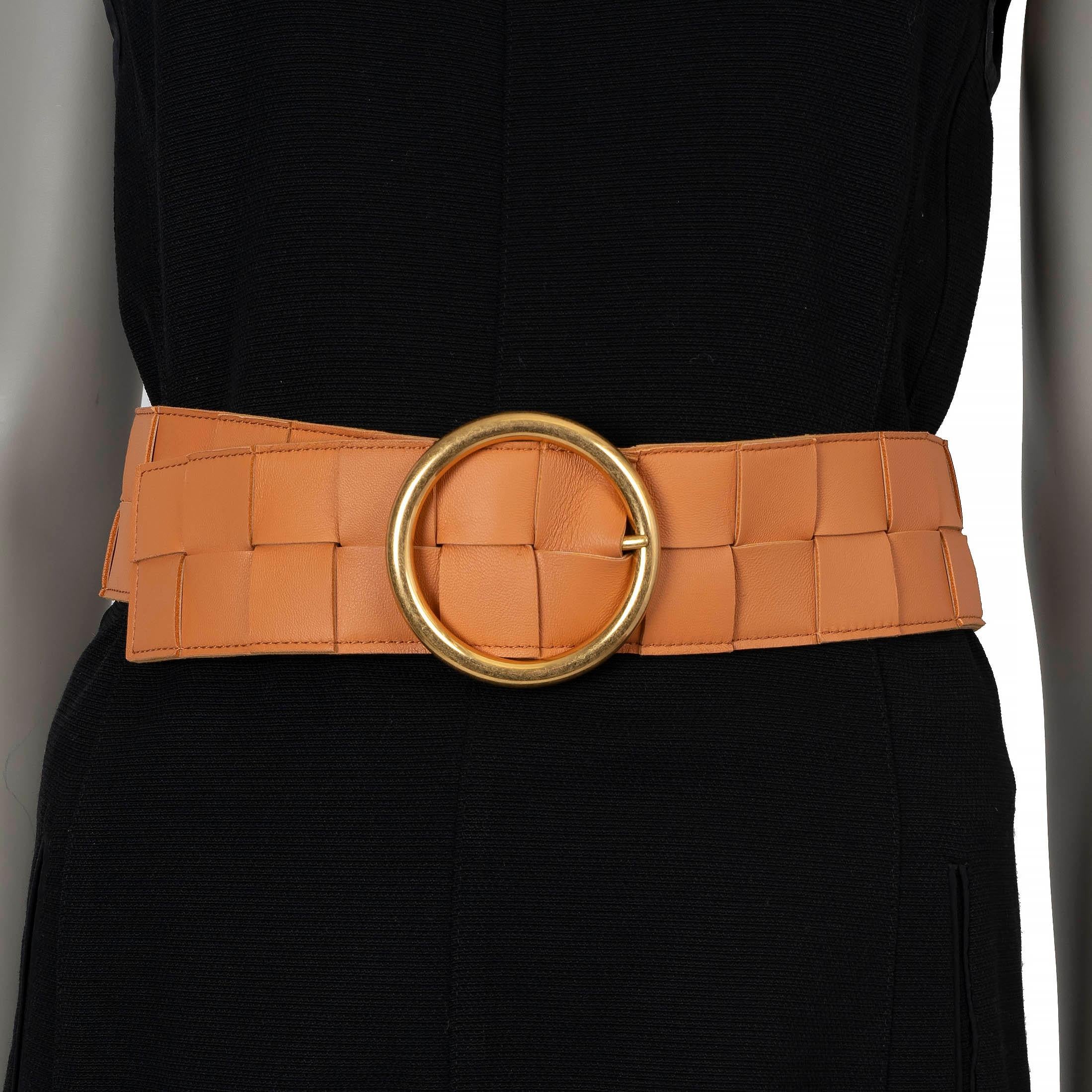 This 100% authentic Bottega Veneta waist belt is crafted from camel brown Maxi Intrecciato woven lambskin Nappa leather, offering a luxurious and textured design. It features a round gold-tone buckle, adding a bold and elegant touch to this timeless