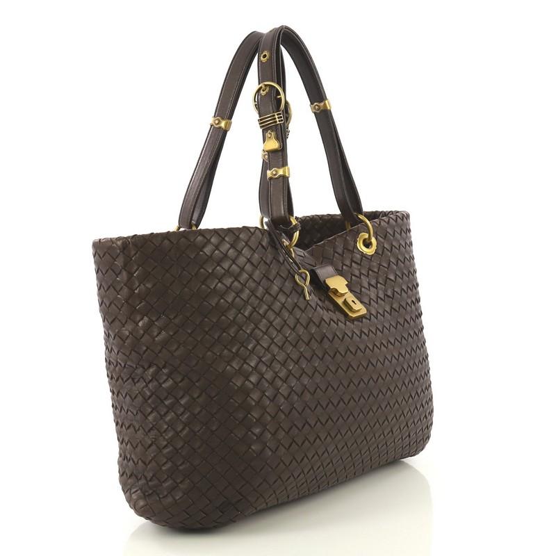 This Bottega Veneta Capri Tote Intrecciato Nappa Large, crafted from brown intrecciato nappa leather, features dual leather handles and aged gold-tone hardware. Its flap tab push-lock closure opens to a neutral microfiber interior with side zip and