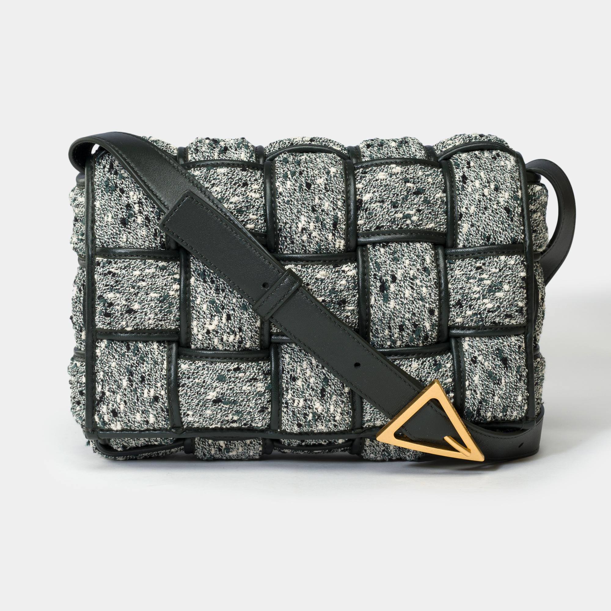 The​ ​Cassette​ ​Crossbody​ ​Bag​ ​by​ ​Bottega​ ​Veneta​ ​is​ ​made​ ​of​ ​grey​ ​and​ ​green​ ​padded​ ​tweed​ ​with​ ​a​ ​black​ ​lambskin​ ​interior,​ ​gold​ ​metal​ ​trim,​ ​adjustable​ ​shoulder​ ​strap​ ​in​ ​black​ ​leather​ ​for​ ​shoulder​