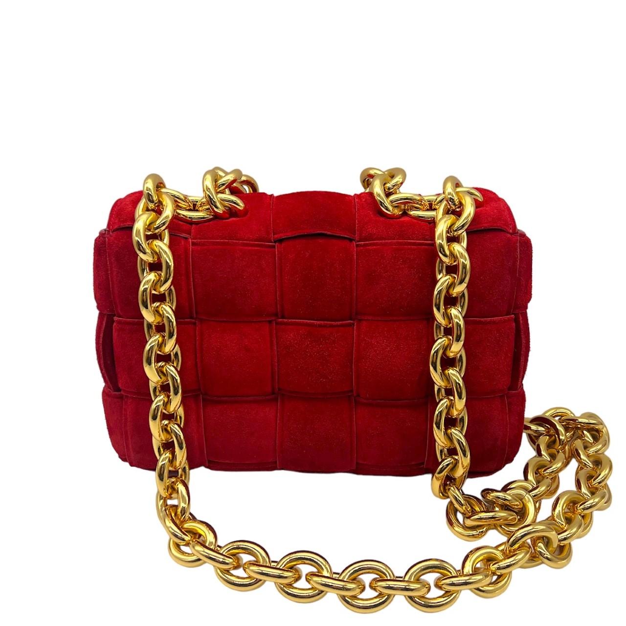 We are offering this coveted red Bottega Veneta crossbody bag. Made in Italy, it is finely crafted of a padded intrecciato suede exterior with leather trims. It has a heavy chain-link handle and shoulder strap made from gold-tone hardware. It