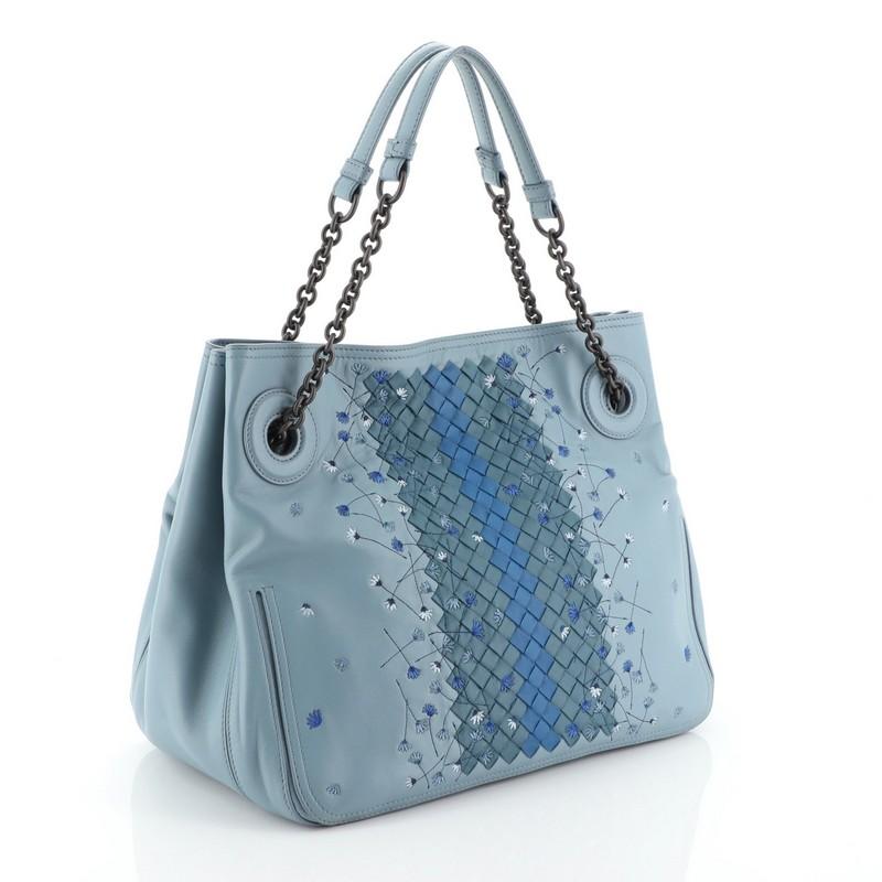 This Bottega Veneta Chain Tote Leather with Embroidery and Intrecciato Detail Medium, crafted in blue leather, features chain link strap with leather pads, embroidery and intrecciato detail, and matte gunmetal-tone hardware. It opens to a neutral