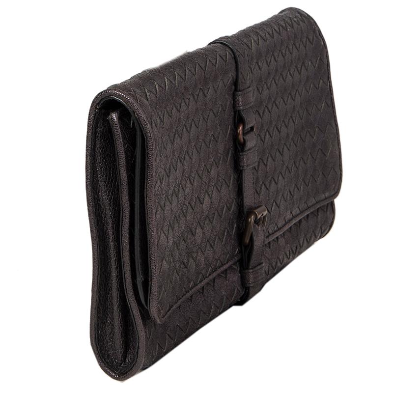Bottega Veneta Intrecciato buckle clutch in charcoal grained leather. Opens with buckel on the front and is lined in light beige suese with one zipper pocket against the back. Clutch is divided in two compartments, one main comparment and one flap