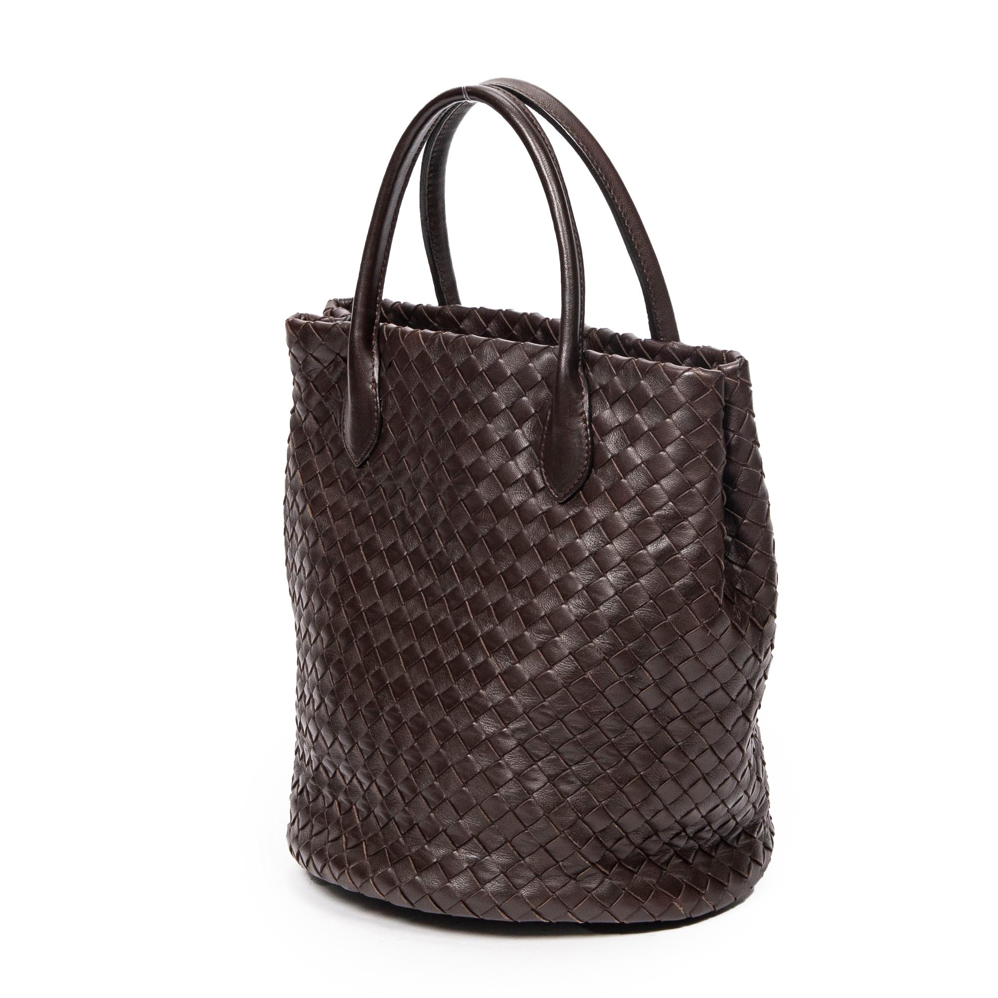 Rich dark brown calfskin leather shapes Bottega Veneta's Chocolate Intrecciato Top Handle Bag, complemented by gold hardware, an open top, and a suede dual-pocket interior.

SPECIFICS
• Length: 8.7