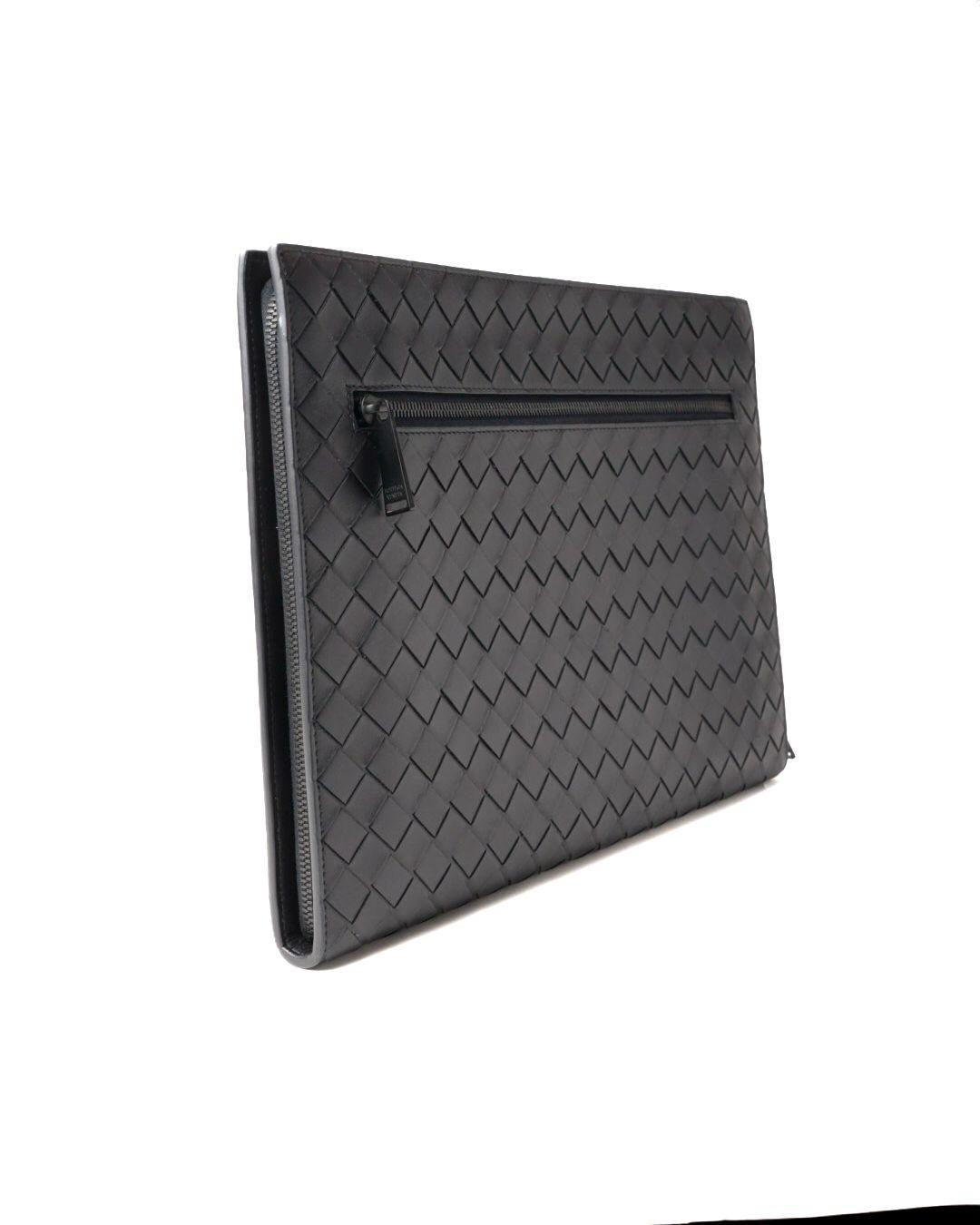 Pochette de Bottega Veneta, réalisée en cuir avec le motif intrecciato caractéristique en bleu nuit et des ferrures ton sur ton. Doté d'une fermeture semi-circulaire à double curseur, doublé intérieurement de toile avec des poches pratiques, assez