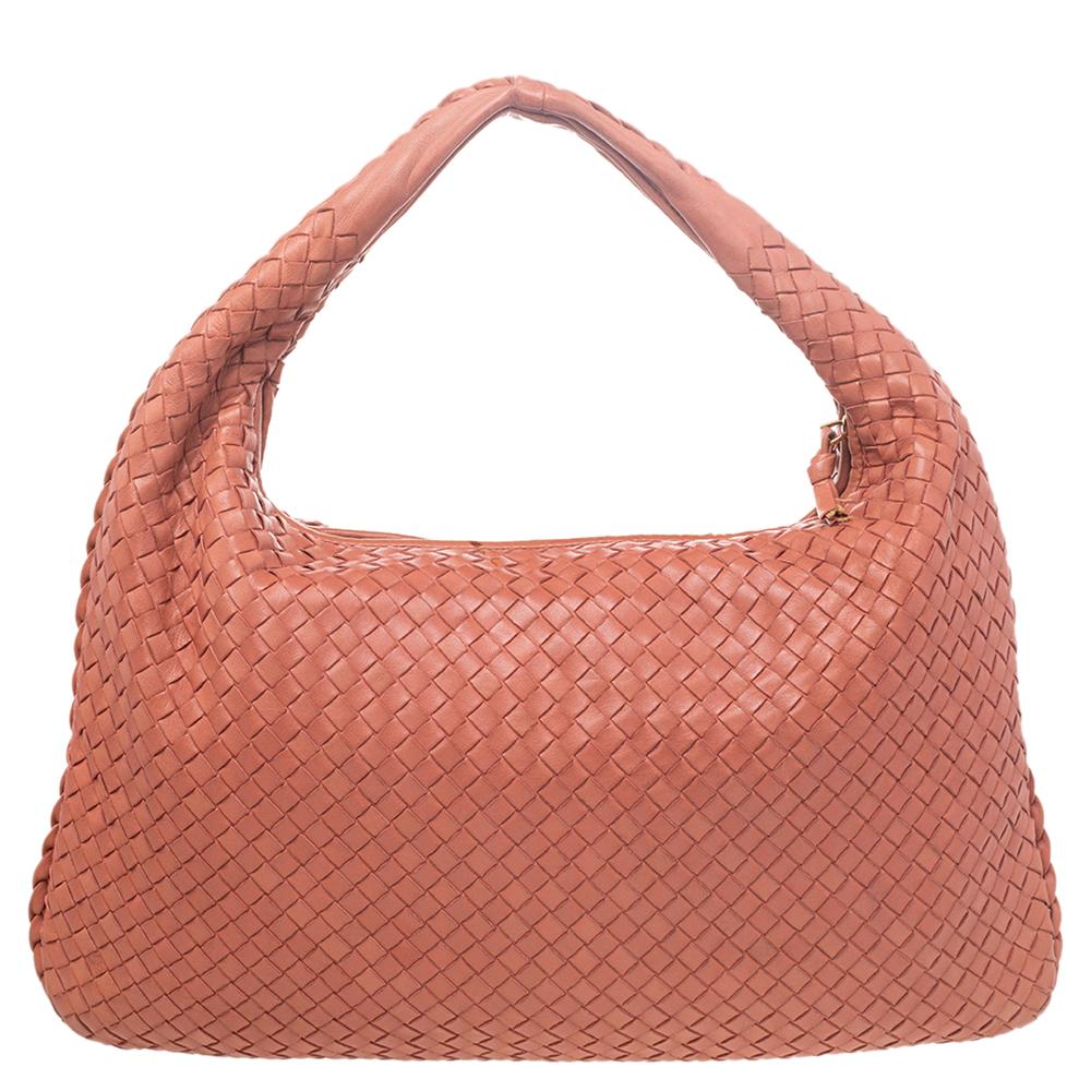 The excellent craftsmanship of this Bottega Veneta hobo ensures a brilliant finish and a rich appeal. Woven from leather in their signature Intrecciato pattern, the coral-hued bag is provided with minimal hardware. It features a loop handle and a