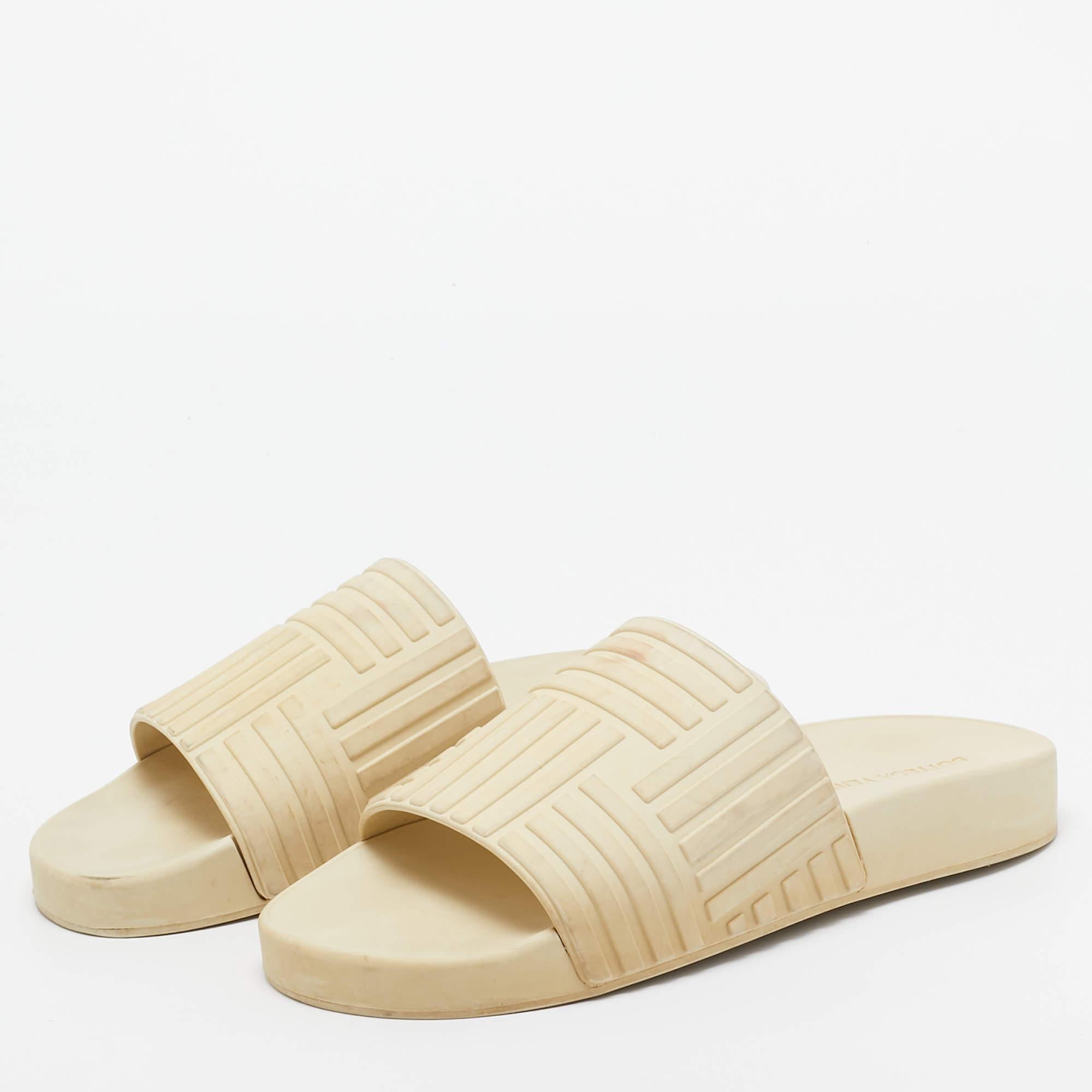 Les diapositives en caoutchouc pour femmes de Bottega Venetas sont présentées dans une teinte crème facile à assortir. Ils sont parfaits pour les vacances à la plage ou pour un usage quotidien.