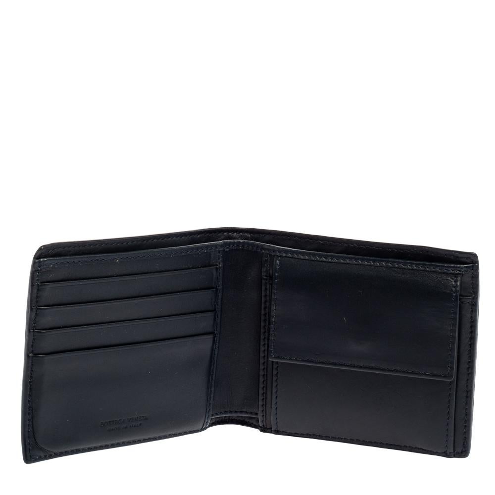 This Bottega Veneta bifold wallet is the most classy way to organize your essentials. The stunning dark blue leather creation is adorned with the signature Intrecciato pattern all over and features two main compartments and multiple card slots to