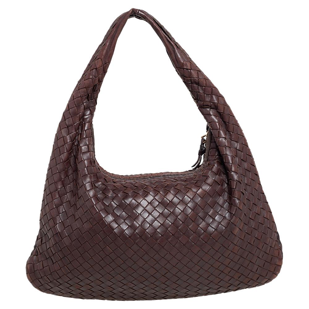 The excellent craftsmanship of this Bottega Veneta hobo ensures a brilliant finish and a rich appeal. Woven from leather in their signature Intrecciato pattern, the dark brown-hued bag is provided with minimal gold-tone hardware. It features a loop