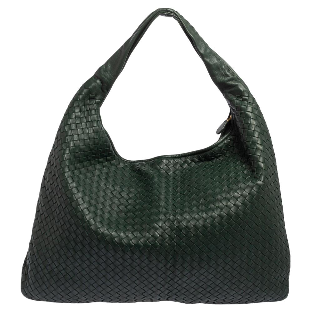 The excellent craftsmanship of this Bottega Veneta hobo ensures a brilliant finish and a rich appeal. Woven from leather in their signature Intrecciato pattern, the dark green-hued bag is provided with minimal gold-tone hardware. It features a loop