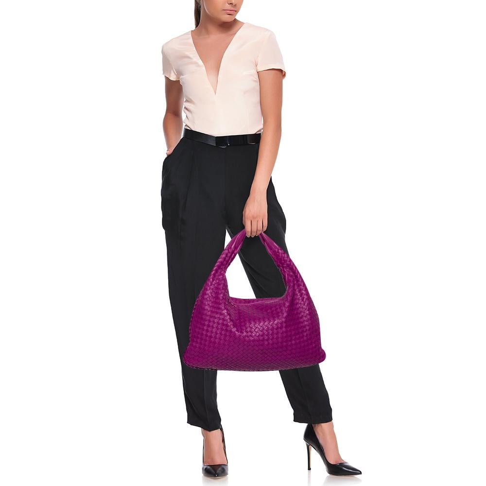 The excellent craftsmanship of this Bottega Veneta handbag ensures a brilliant finish and a rich appeal. Woven from leather in their signature Intrecciato pattern, the magenta bag is provided with minimal bronze-tone hardware. It features a loop