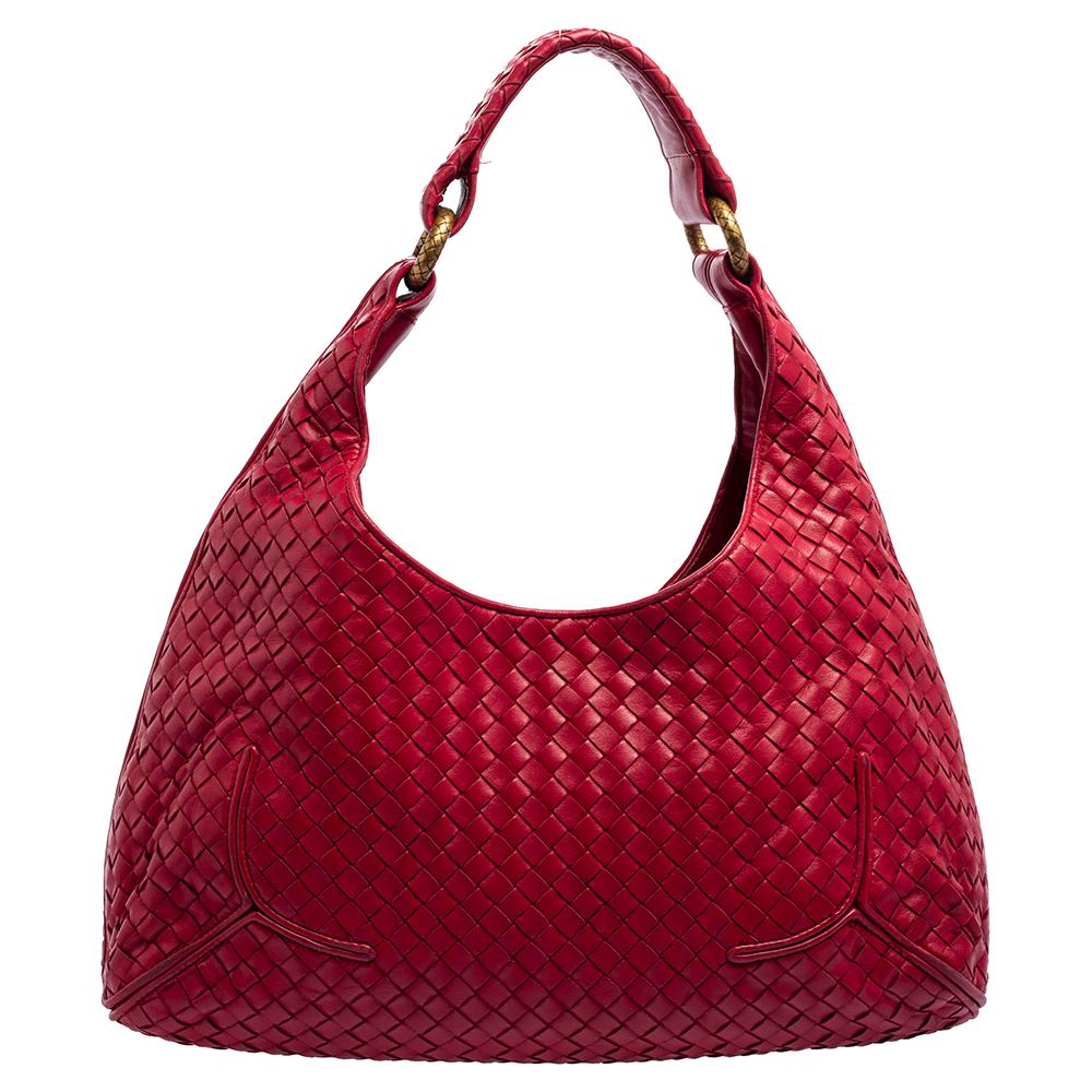 Crafted from fine leather, this Bottega Veneta hobo is truly stunning! Its Intrecciato weave on the exterior adds the brand's signature design. The single leather handle is coupled with oversized gold-tone rings. The dark pink bag includes a mirror