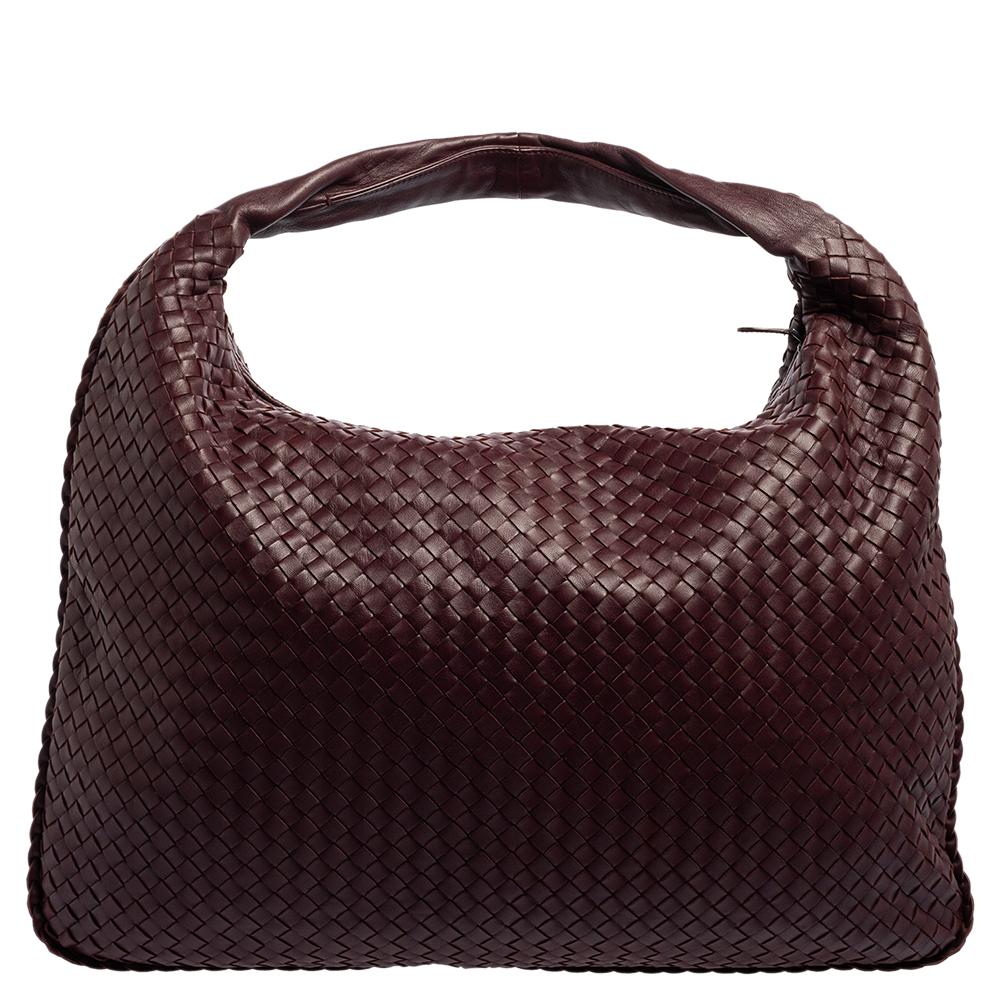 The excellent craftsmanship of this Bottega Veneta hobo ensures a brilliant finish and a rich appeal. Woven from leather in their signature Intrecciato pattern, the dark purple-hued bag is provided with minimal gold-tone hardware. It features a loop