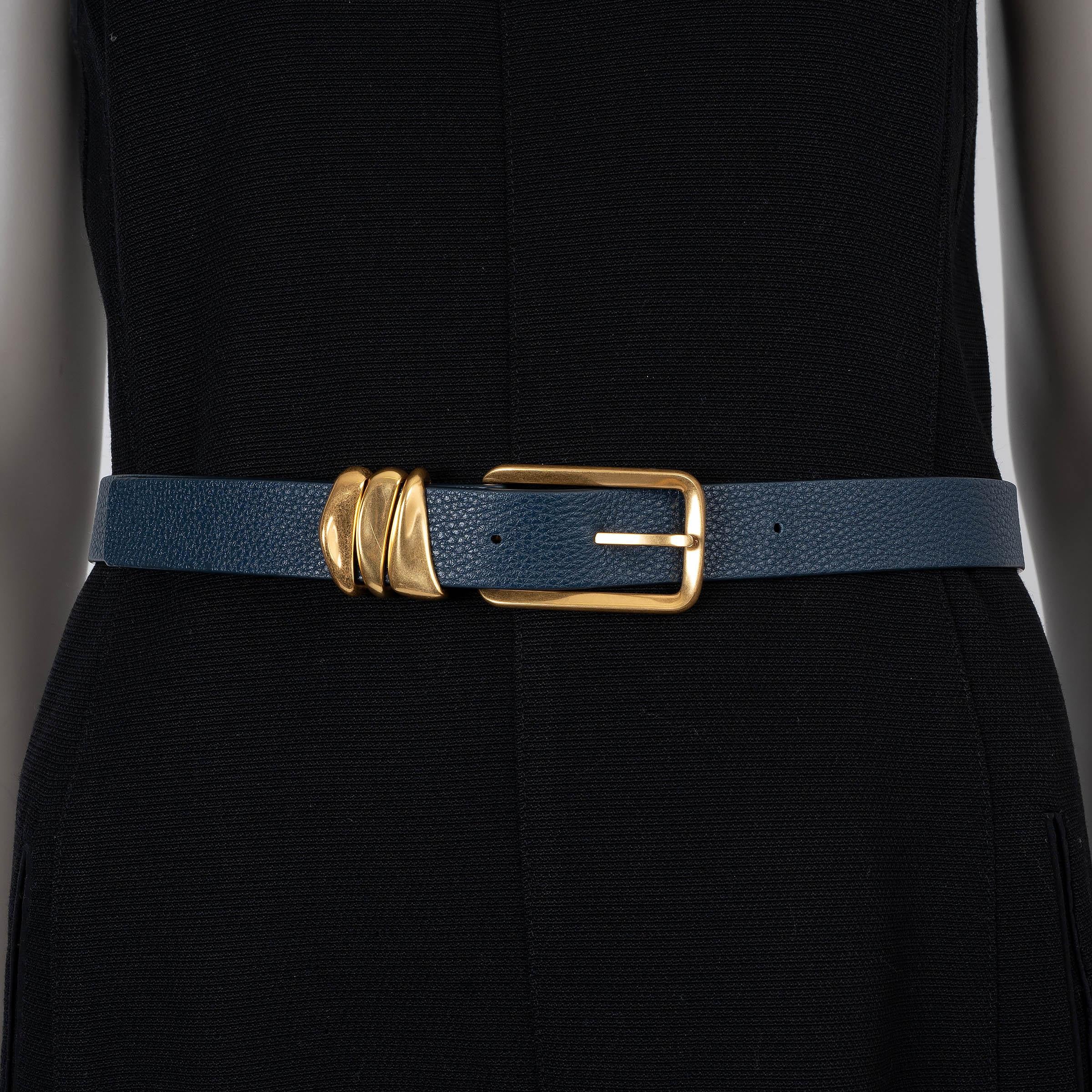 Cette ceinture Bottega Veneta 100 % authentique en cuir bleu foncé (pétrole) incarne la sophistication discrète. Doté d'une boucle en métal doré et d'un fermoir rectangulaire arrondi, il allie harmonieusement élégance contemporaine et savoir-faire