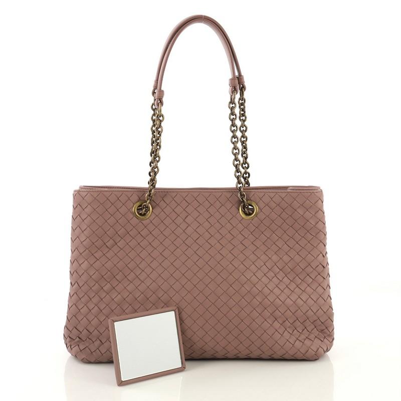 This Bottega Veneta Double Chain Tote Intrecciato Nappa Medium, crafted from pink intrecciato nappa leather, features dual chain link handles with leather pads and aged gold-tone hardware. Its magnetic snap closure opens to a neutral suede interior