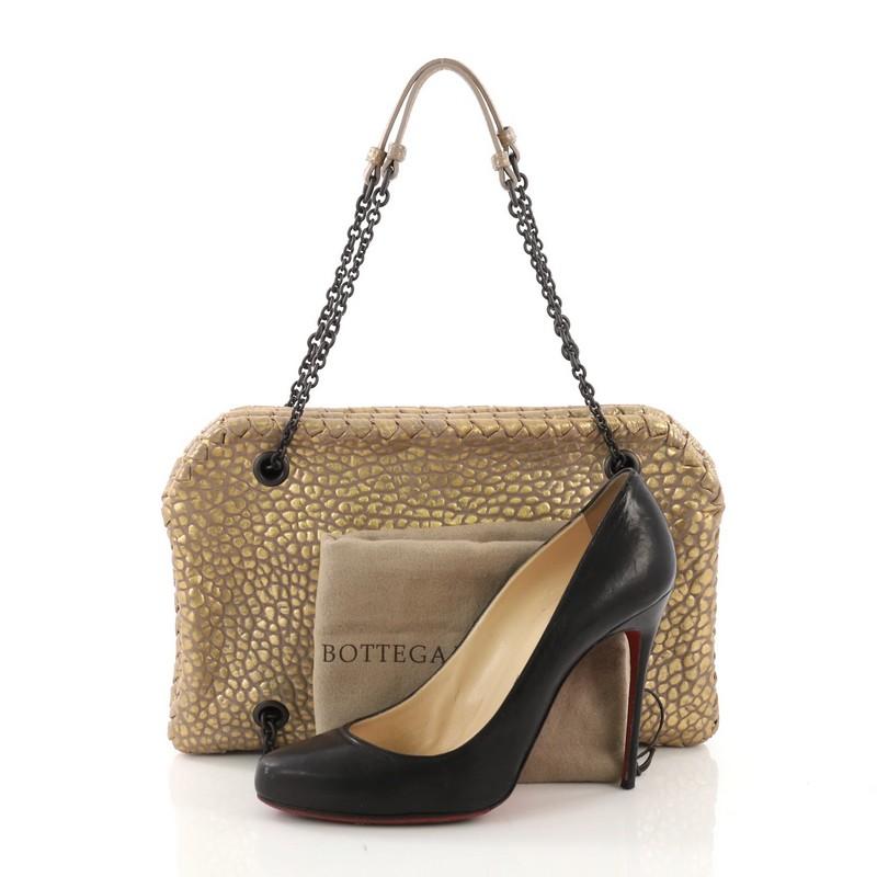 This Bottega Veneta Duo bag Intrecciato Nappa, crafted with gold intrecciato nappa leather, features chain straps threaded through rings across the top and bottom and gunmetal-tone hardware. Its hidden magnetic snap closure opens to a taupe