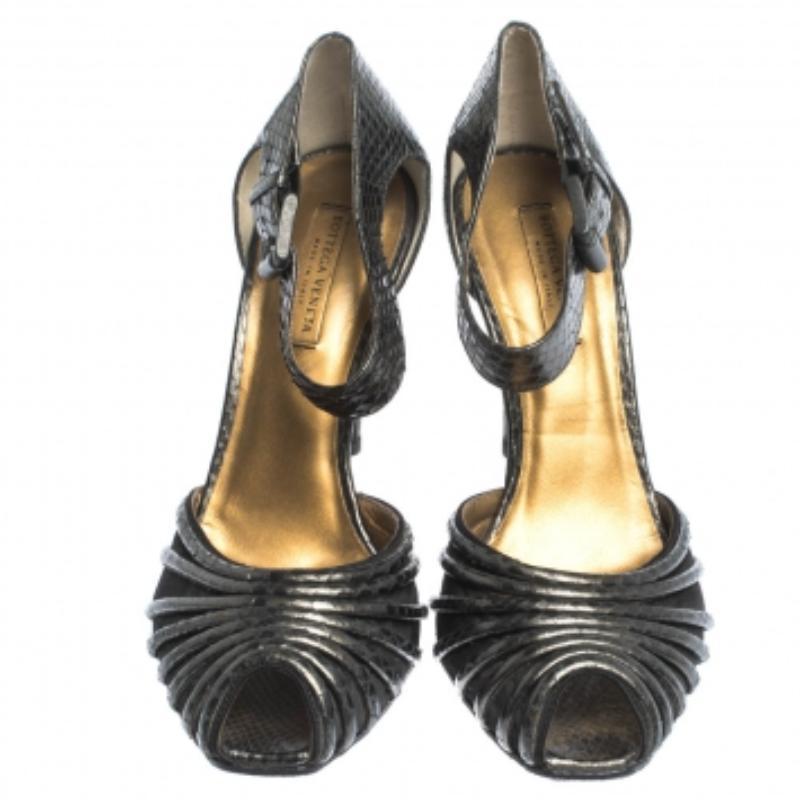 Estas sandalias elegantes y con clase proceden de la casa Bottega Veneta. Están confeccionados en piel de pitón gris repujada y satén, con puntera abierta. Tienen contrafuertes cubiertos, correas abrochadas en el tobillo, tacones de 10 cm y