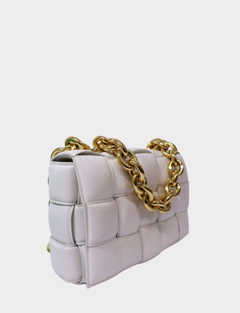 Elevate your wardrobe with the iconic Bottega Veneta Chain Cassette Bag in white. Handwoven with the brand's signature Intrecciato technique, this luxurious shoulder bag features a buttery-soft padded leather body and bold gold-tone chain strap for