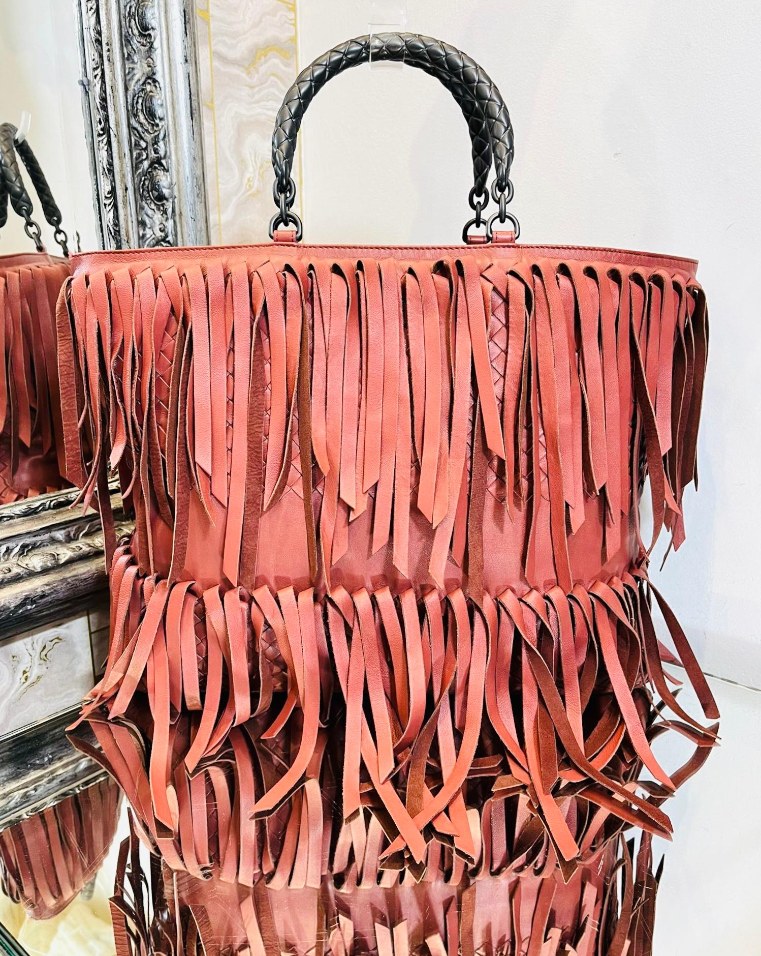 Bottega Veneta Fringe Intrecciato Leather Tote Bag

Rusty pink large bag designed with fringe details.

Styled with dual, rolled top handle crafted from the brand's signature Intrecciato leather in metallic grey.

Having spacious suede line interior