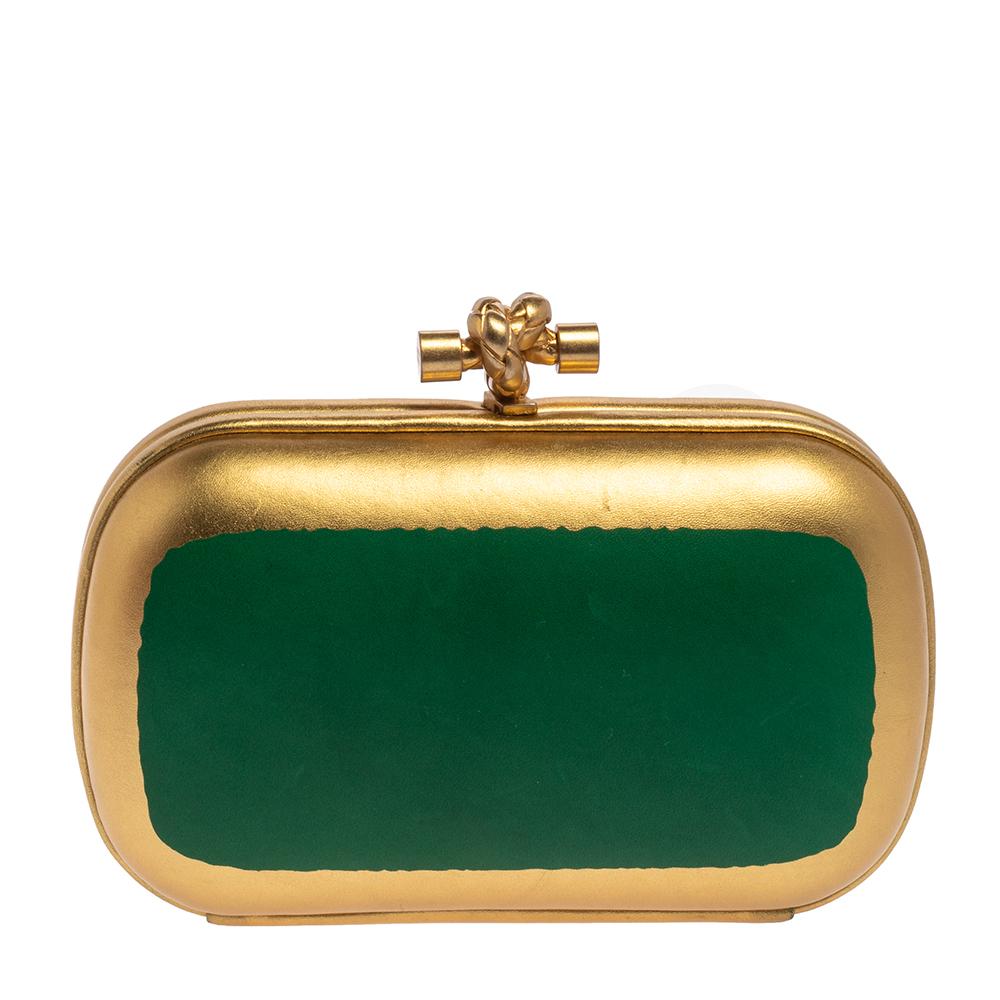 The Knot clutch for women is one of Bottega Veneta's most loved accessories. Updated in green and gold leather, this version has the signature shape and the iconic knot motif on top. The interior is lined with suede to protect your