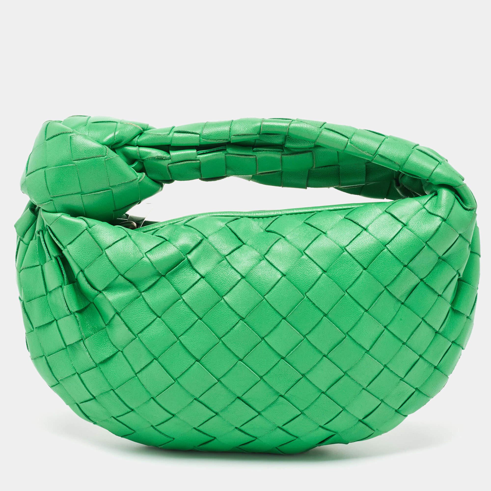 The Bottega Veneta Jodie hobo is a luxurious and compact handbag crafted from exquisite green leather woven in the brand's signature Intrecciato pattern. It features a relaxed hobo silhouette, a single top handle, and a zip closure, making it both