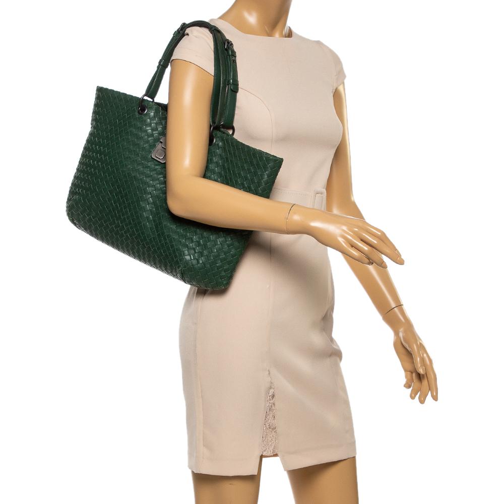 Let your style speak about your choices as you carry this Bottega Veneta Shopper tote. Crafted from the signature intrecciato woven leather, the exterior features a pretty green hue all over. It is accented with top handles and black-tone hardware.