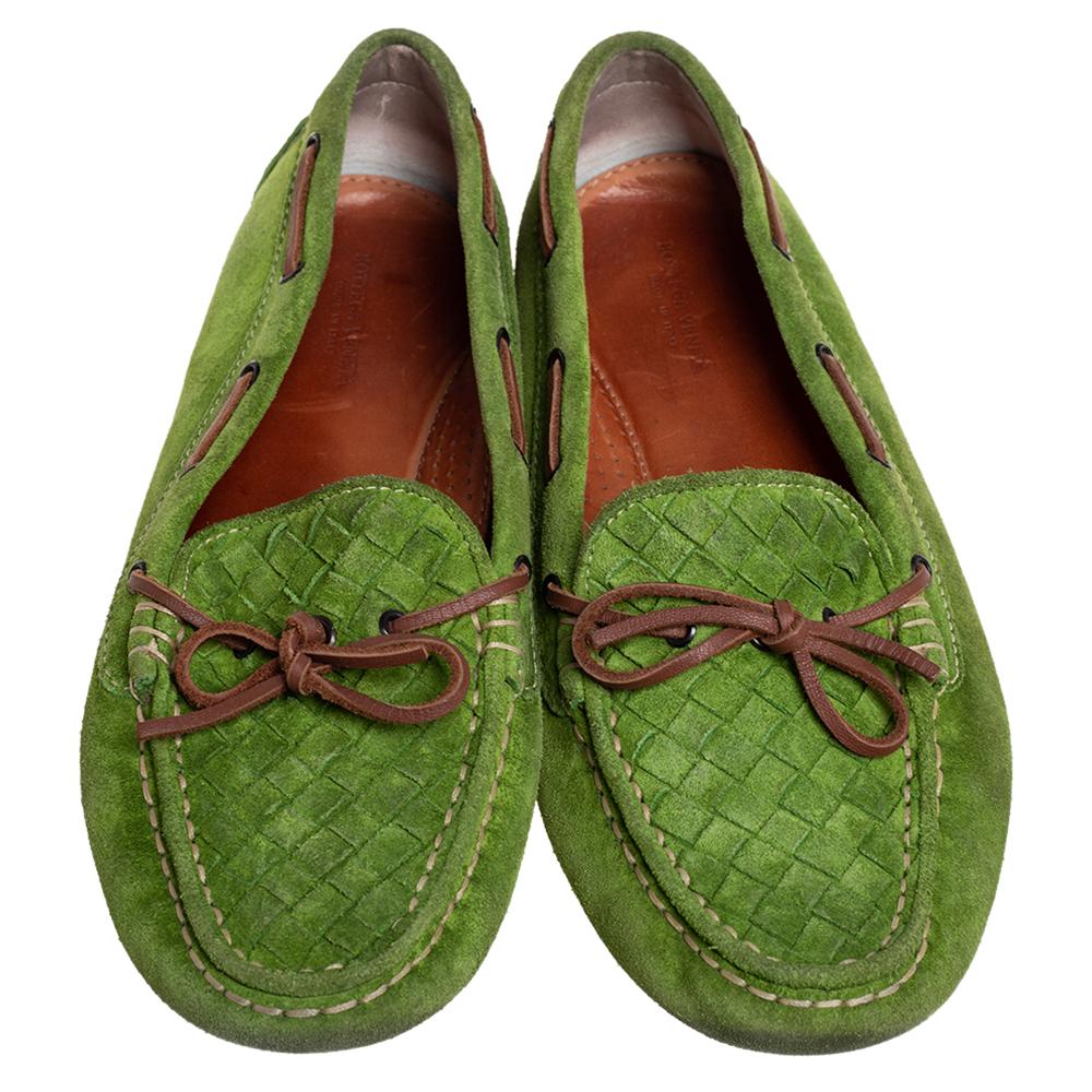 If you are on the lookout for snug, classy, and one-of-a-kind footwear, this Bottega Veneta creation is just for you. These green Intrecciato suede loafers are the perfect blend of comfort. With their brown leather detailing, bows on the uppers, and